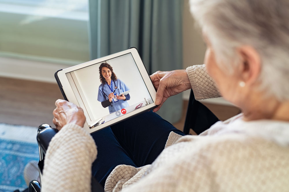 Idoso recebendo auxílio via tablet de um serviço de Teleassistência.