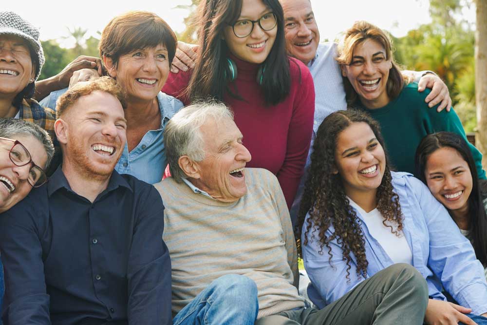 Senhor rodeado de amigos e familiares em foto no jardim.