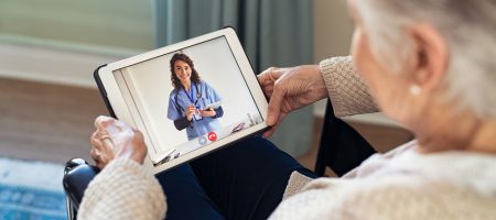 Idoso recebendo auxílio via tablet de um serviço de Teleassistência.